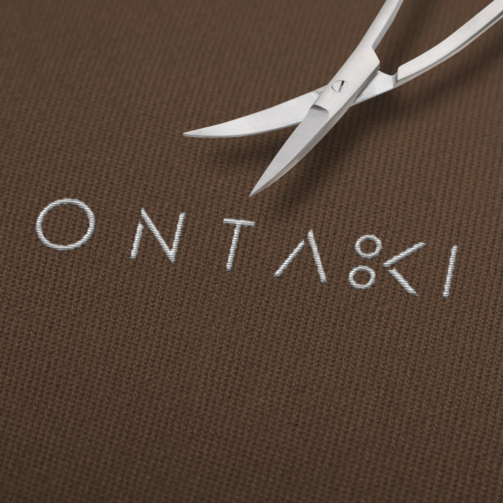 Curved fabric scissors with precision tip on embroidered ONTAKI fabric.
