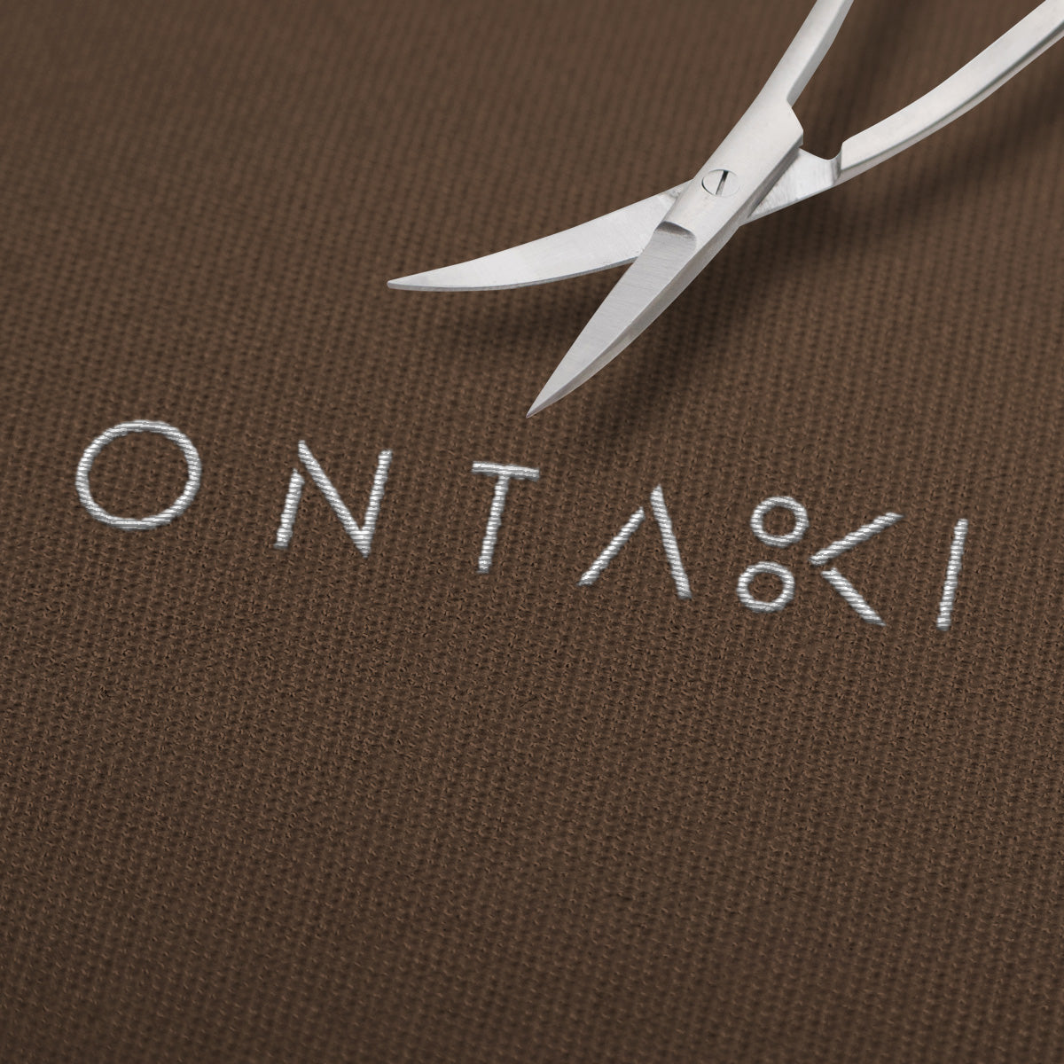 Curved fabric scissors with precision tip on embroidered ONTAKI fabric.