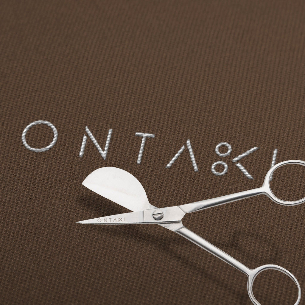 Duckbill Scissors on brown fabric background.