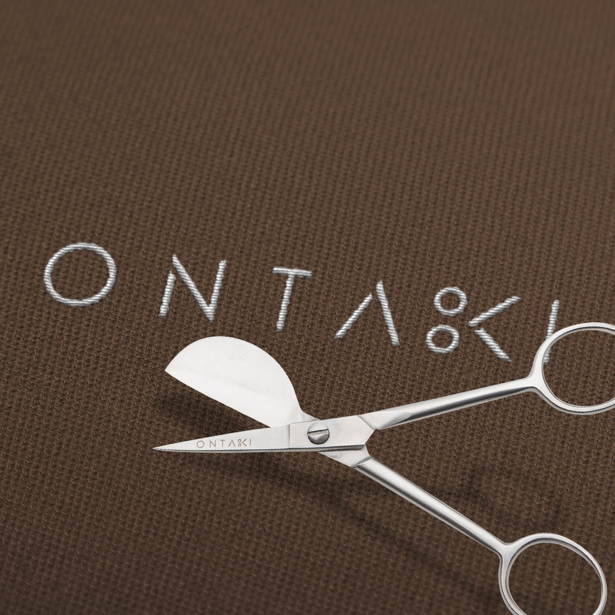 Duckbill Scissors on brown fabric background.